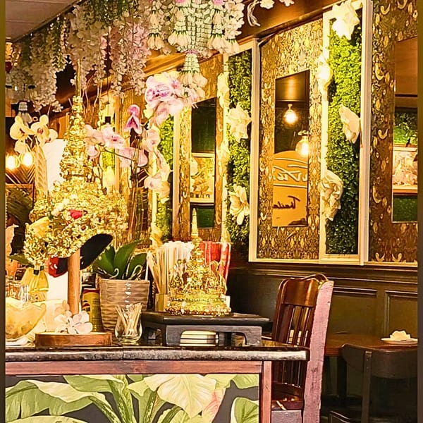 Intricate gold decor, orchids, and hanging floral arrangements adorn the interior of Sampannee Thai restaurant.