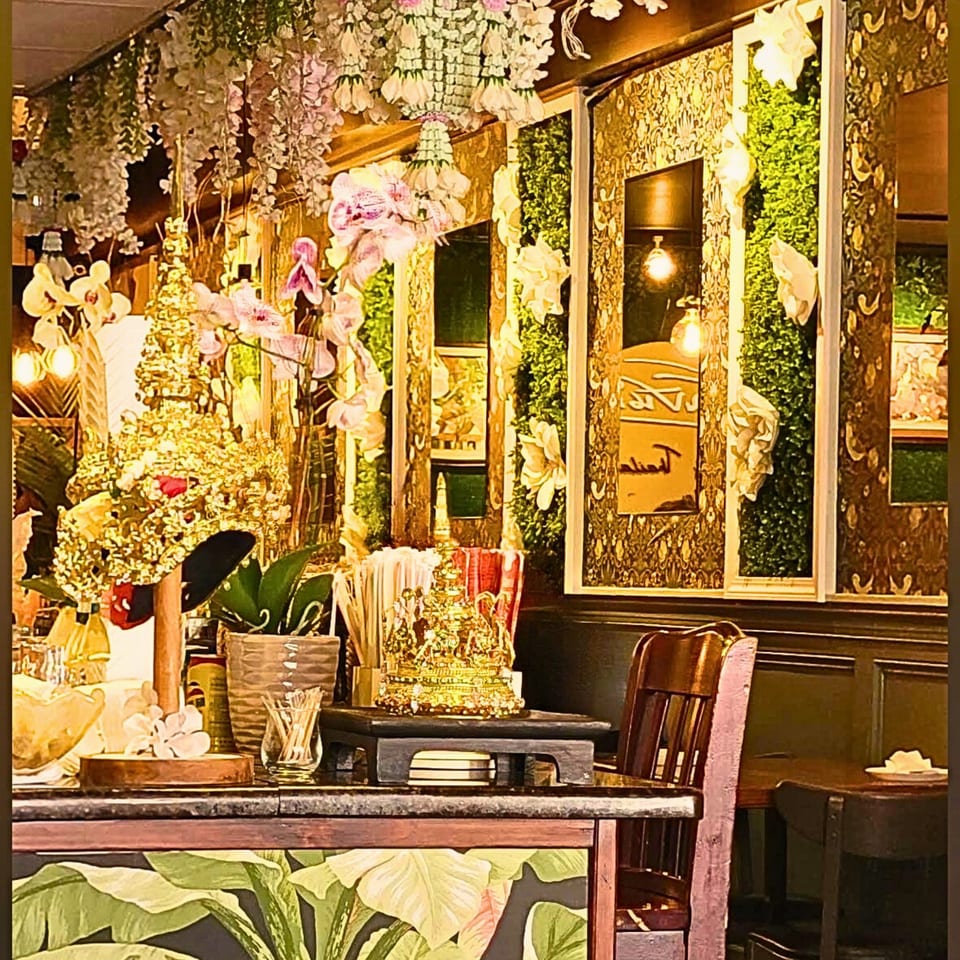 Intricate gold decor, orchids, and hanging floral arrangements adorn the interior of Sampannee Thai restaurant.